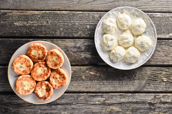 Cheesecakes ahşap rustik masa üzerinde. Geleneksel olarak, Rus ham ve kızarmış krep süzme peynir ile. Pişirme işlemi. Üstten Görünüm. 