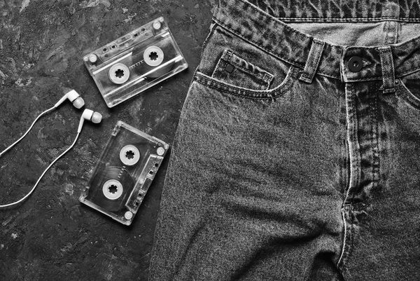 牛仔裤 录音带 耳机布局在一个黑色的混凝土桌上 概念照片 说明了听音乐的魅力 顶部视图 — 图库照片