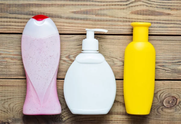 Botellas de productos para el baño. Gel de ducha, jabón líquido, champú en una mesa de madera. Vista superior . —  Fotos de Stock