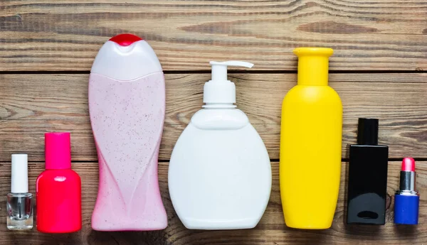 Produtos para tomar banho em garrafas e cosméticos de mulher em uma mesa de madeira. Cuidados pessoais. Objetos para higiene e beleza. Vista superior. Depósito plano . — Fotografia de Stock