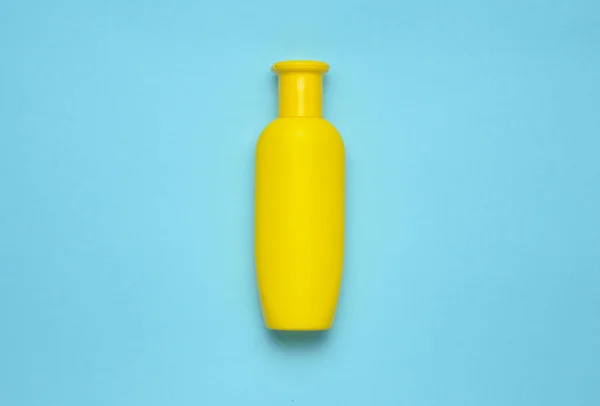 Gele fles shampoo op een blauwe achtergrond. Trend van minimalisme. Bovenaanzicht. Producten voor de douche. Ruimte voor tekst. — Stockfoto