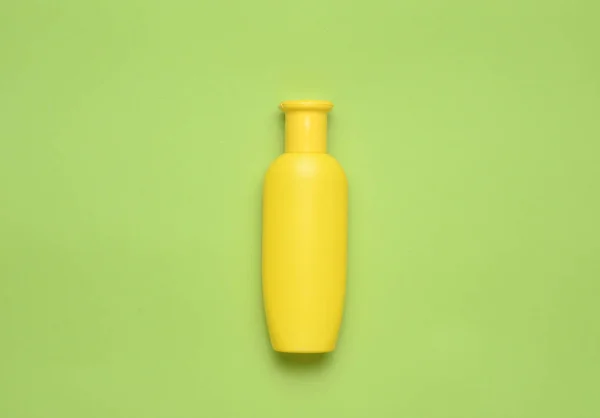 Gele fles shampoo op een groene achtergrond. Trend van minimalisme. Bovenaanzicht. Producten voor de douche. Ruimte voor tekst. — Stockfoto