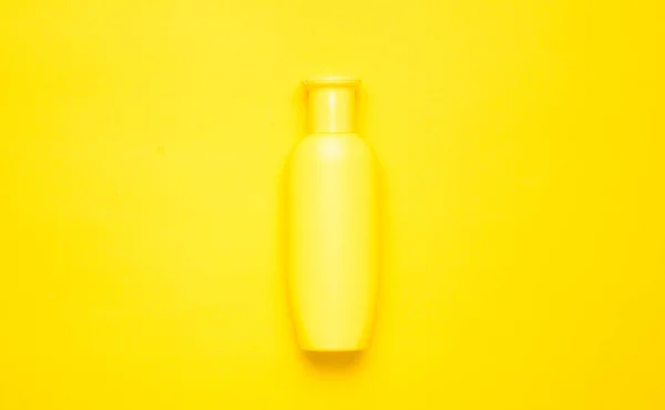 Bouteille jaune de shampooing sur fond jaune. Tendance au minimalisme. Vue de dessus. Produits pour la douche. Espace pour le texte . — Photo