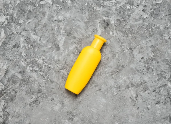 Uma garrafa amarela de champô numa mesa de betão cinzento. Tendência do minimalismo. Vista superior. Produtos para o chuveiro. Espaço para texto . — Fotografia de Stock