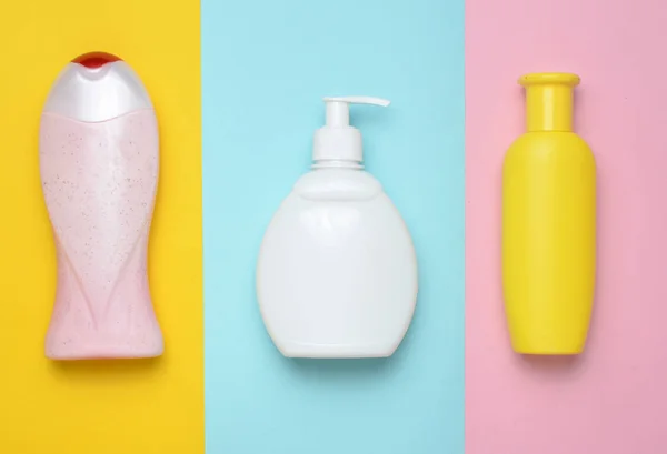 Flaschen Produkte für Dusche und Bad auf einem mehrfarbigen Pastellhintergrund. Shampoo, Flüssigseife, Duschgel. Ansicht von oben. flach lag. Trend zum Minimalismus. — Stockfoto