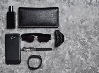 Aksesuar ve gadget'lar için beton yüzeyinde bir iş kadını. Akıllı telefon, akıllı bilezik, kalem, parfüm şişesi, çanta, güneş gözlüğü. Üstten Görünüm. Metin için yer.