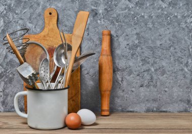 Beton duvar arka plan üzerinde ahşap bir masa pişirme için mutfak araçları. Uzay kopyalayın. Kaşık, çatal, tahta spatula, oklava, yumurta.