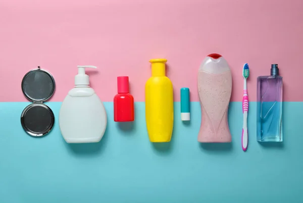 Champú, perfume, lápiz labial, gel de ducha, cepillo de dientes. Productos para la belleza, el cuidado personal y la higiene sobre un fondo de pastel azul rosado. Vista superior. Puesta plana . — Foto de Stock