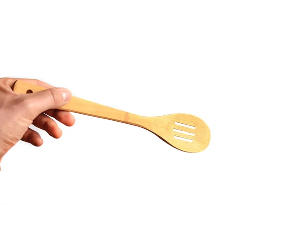 La mano di un uomo tiene una spatola di legno isolata su uno sfondo bianco. Utensili da cucina per cucinare . — Foto Stock