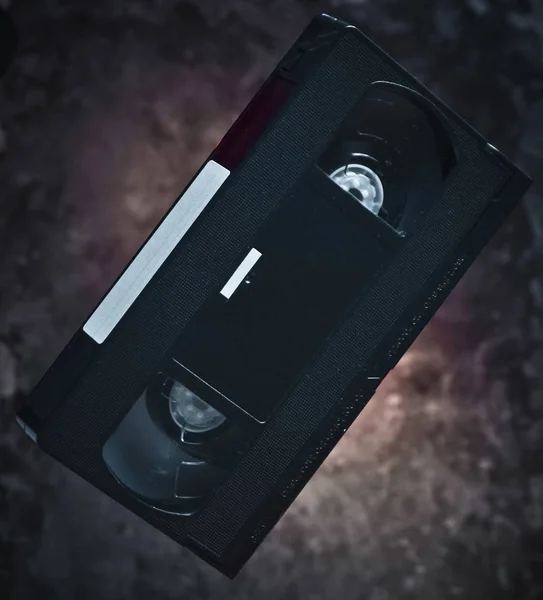 Videocasete de levitación en el fondo de una pared de hormigón oscuro. Luz mística. Tecnología retro de los años 80 . — Foto de Stock