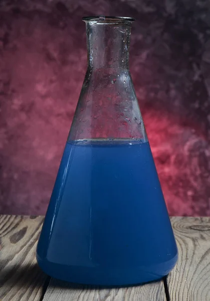 コンクリートの壁に木製の棚の青い液体で実験室のフラスコ — ストック写真