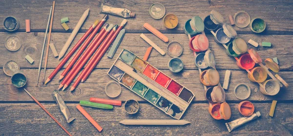 Tools for the artist. Objects for drawing. Paint, crayons, pencils on a wooden table. Inspiration to create. Top view. Flat lay.