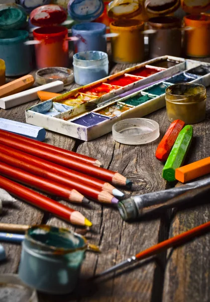 Tools for the artist. Inspiration to create. Objects for drawing. Paint, crayons, pencils on a wooden table.