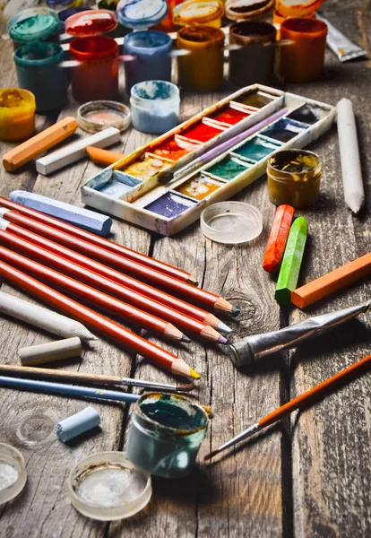 Tools for the artist. Inspiration to create. Objects for drawing. Paint, crayons, pencils on a wooden table.