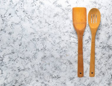 Tahta bir spatula ve beyaz beton zemin üzerinde tava üzerinde kızartma için bir kaşık. Üstten Görünüm. Kopya alanı.