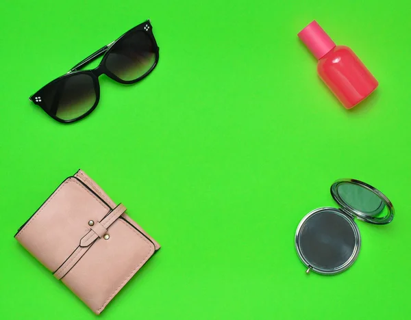 Copia el espacio de diseño de accesorios de moda femenina sobre un fondo verde. Espejo, gafas de sol, bolso, frasco de perfume. Vista superior . —  Fotos de Stock