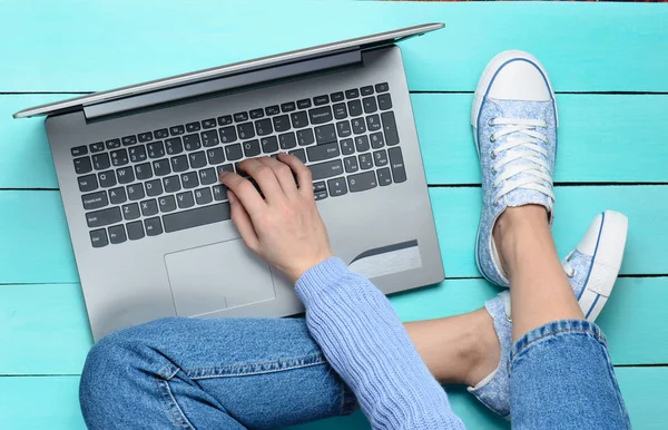 Utilizzando un computer portatile su un tavolo di legno turchese. Vista dall'alto. Gioventù moderna. Generazione z. Lavoro online su Internet . — Foto Stock