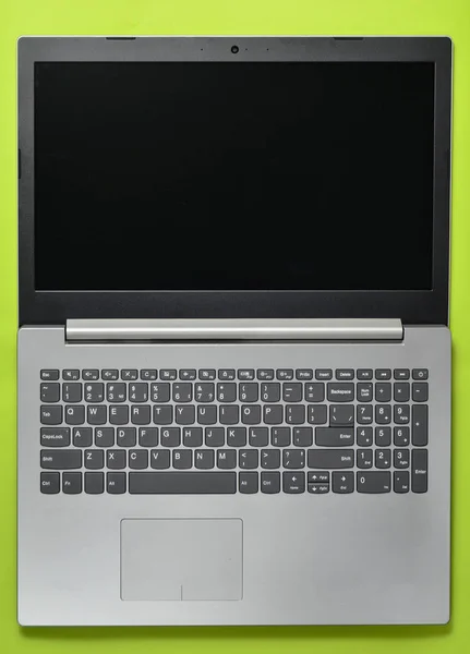 Otwórz laptopa na zielonym tle. Nowoczesne technologie komputerowe. Widok z góry. — Zdjęcie stockowe