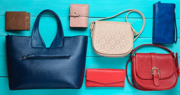 Many women's bags and purses on a blue wooden background. Top view.