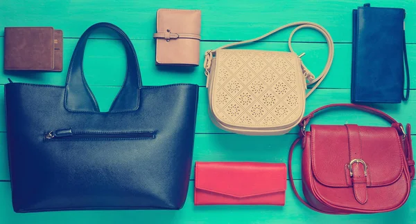 Many women's bags and purses on a blue wooden background. Top view.