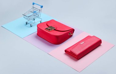 Alışverişkolik minimalist kavram. Çanta, çanta, pastel arka planda mini alışveriş arabası. Yan görünüm