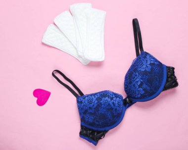 Kadınların kritik günleri, adet günleri. Minimalist kadın hijyen konsepti. Güzel seksi bir sütyen, pastel arka planda iç çamaşırları. Düz yatıyordu