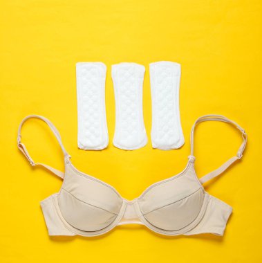 Kadınların kritik günleri, adet günleri. Minimalist kadın hijyen konsepti. Güzel seksi sutyen, sarı arka planda külotlu çorap. Üst görünüm