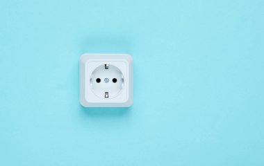 Mavi arka planda beyaz plastik priz. Kopya alanı olan duvar. Minimalizm