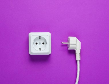 Beyaz plastik priz ve mor arka planda elektrik prizi. Üst görünüm