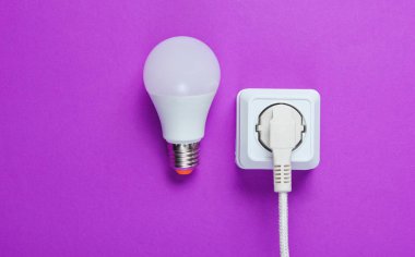 Elektrik prizine takılı beyaz kablo ve mor arka planda lamba. Üst görünüm