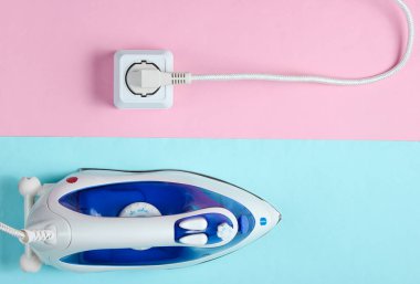 Pastel arka planda elektrik prizine takılan şeyleri ütülemek için kablo demiri. Üst görünüm, minimalizm