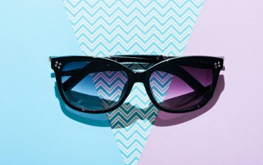 Yaratıcı pastel arka planda modaya uygun güneş gözlükleri. Üst görünüm