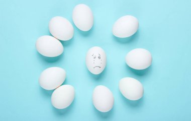 Mavi arka planda yumurtalarla zorbalık kavramı. Üst görünüm, minimalizm