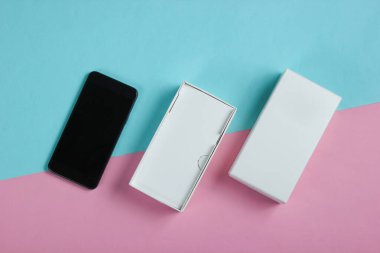 Renkli pastel arka planda açık kutuda yeni akıllı telefon. Üst görünüm, minimalizm