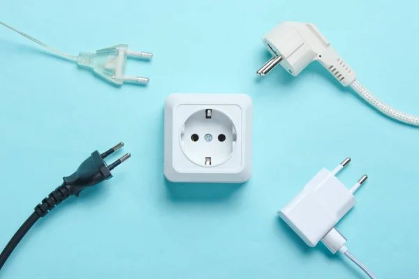 Elektrik bağımlılığı kavramı. Mavi arkaplanda elektrik prizlerinin yanında bir sürü elektrik prizi var