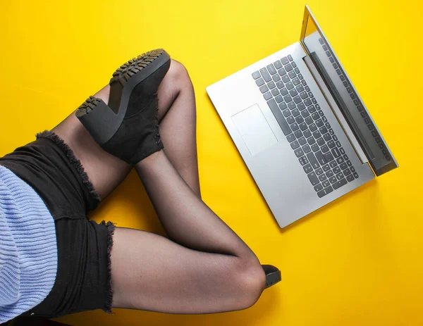 Модна Жінка Шортах Колготках Чоботях Використовує Ноутбук Сидячи Жовтому Тлі — стокове фото