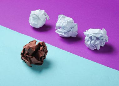 Eşsizlik kavramı, ırk ayrımcılığı. Mor mavi arka planda beyaz ve kahverengi buruşuk kağıt toplar. Minimalizm işi
