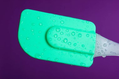 Mor zemin üzerinde su damlalarında yemek pişirmek için silikon mutfak spatulası