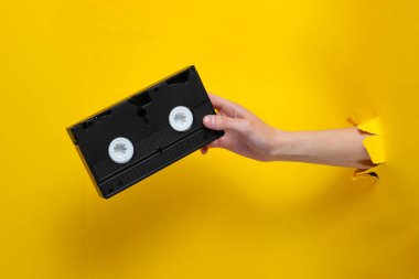Kadın elinde yırtık sarı kağıttan yapılmış kaset var. Asgari retro kavramı