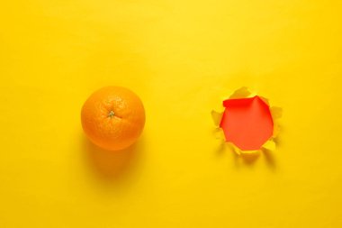 Turuncu ve sarı kağıtta yırtık bir delik. Minimalist meyve kavramı