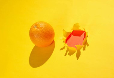 Turuncu ve sarı kağıtta yırtık bir delik. Minimalist meyve kavramı