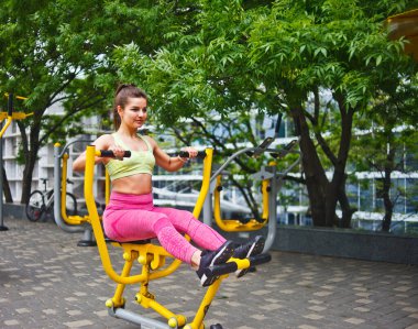 Spor sahasında egzersiz makineleri üzerinde egzersiz yapan çekici atletik kadın.