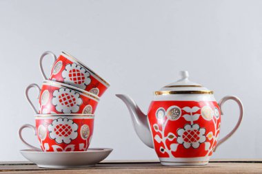 Antika seramik bardaklar ve çaydanlık beyaz bir duvara karşı ahşap masa