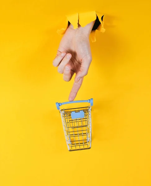 Mano Femenina Toca Mini Carrito Compras Través Papel Amarillo Roto — Foto de Stock