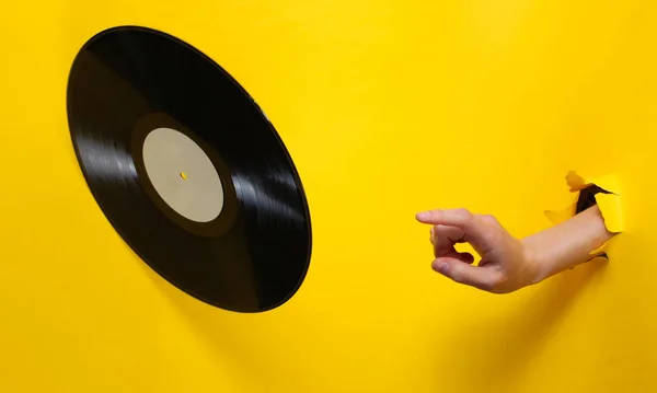 Samičí Ruka Otáčí Vinylovou Desku Přes Pozadí Roztrhaného Žlutého Papíru — Stock fotografie