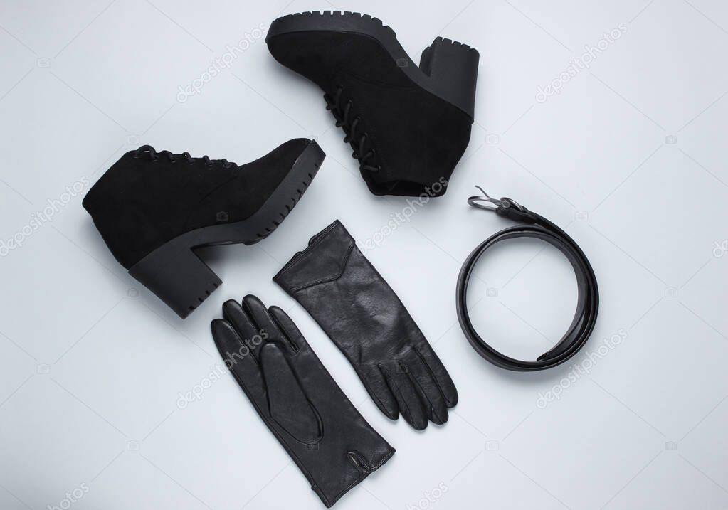 Fashionable women's shoes and accessories. Boots,  leather belt and gloves on gray background. Top view
