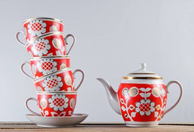 Antika seramik bardaklar ve çaydanlık beyaz bir duvara karşı ahşap masa