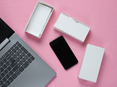 Boksu açma, tekno blog yazma kavramı. Yeni akıllı telefonlu bir kutu, pastel arka planda bir laptop. Üst görünüm