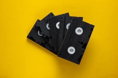 Sarı arka planda bir yığın retro video kaseti. Üst görünüm