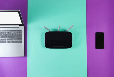 Wi-fi yönlendirici, akıllı telefon, renkli arka planda dizüstü bilgisayar. Modern aletler. Üst görünüm